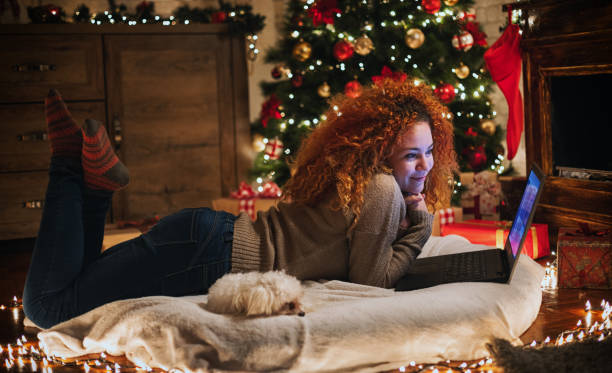 istock Young beautiful girl enjoying at home while using laptop in a cozy Christmas atmosphere 1282367553