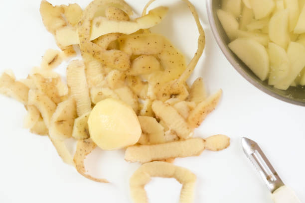 pelures et pelées et coupées de pommes de terre sur une table blanche, concept de plats de légumes cookinf - root vegetable raw potato human skin root photos et images de collection
