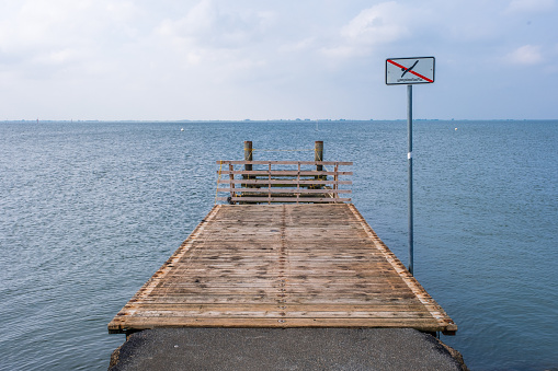 A wooden pier on the North Sea coast with a sign bathing is prohibited.