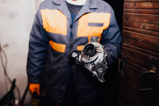 male master auto mechanic holds a car water pump in his hand. stock photo