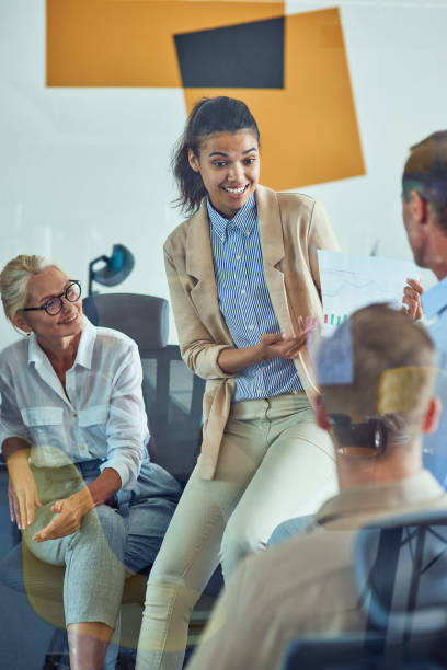 istock Young cheerful mixed race female office worker discussing sales report with colleagues while having a meeting in the modern office 1282373105