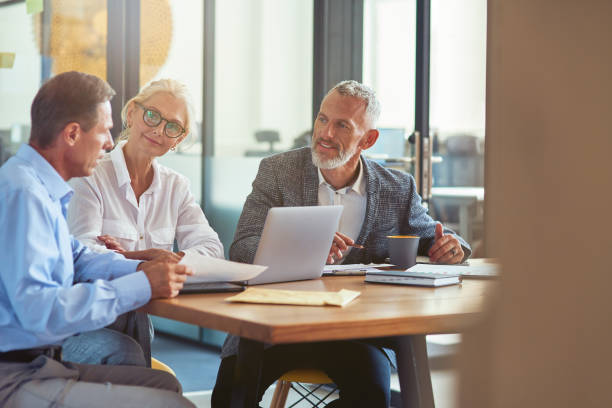 istock Three mature colleagues sitting in the modern office and discussing business strategy, business people working together 1282373108