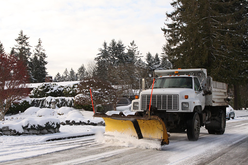 A snow plow truck on a city street in winter