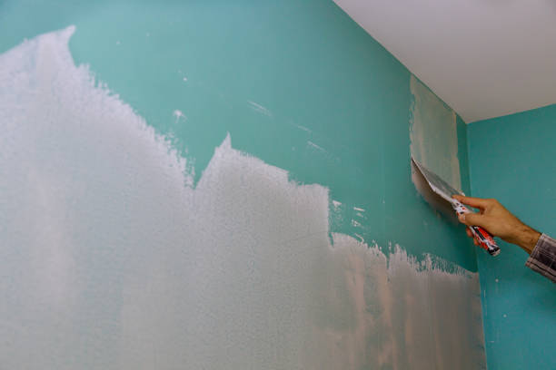 istock Professional builder smooths wall with spatula putty put on leveled surface of wall. 1282377442