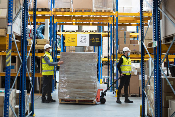 istock Group of workers with face mask working indoors in warehouse, coronavirus concept. 1282377865