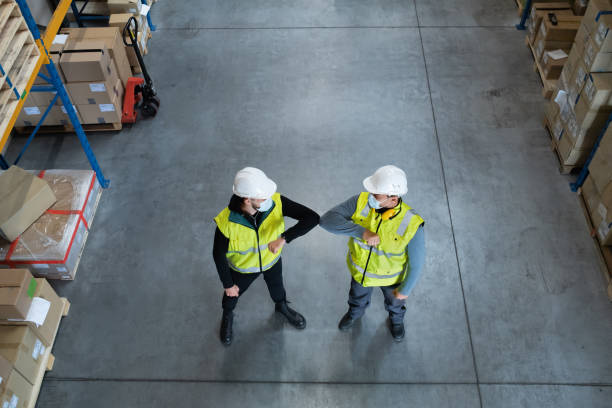 top view workers with face mask greeting indoors in warehouse, coronavirus concept. - manual worker handshake industry warehouse imagens e fotografias de stock