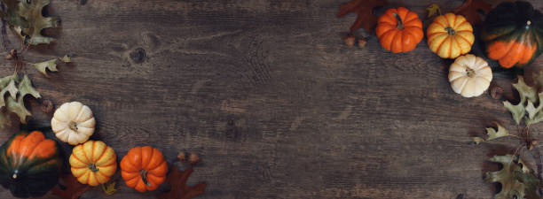 istock Fall Thanksgiving pumpkins, leaves, acorn squash border over rustic dark wood table background shot from directly above 1282379991