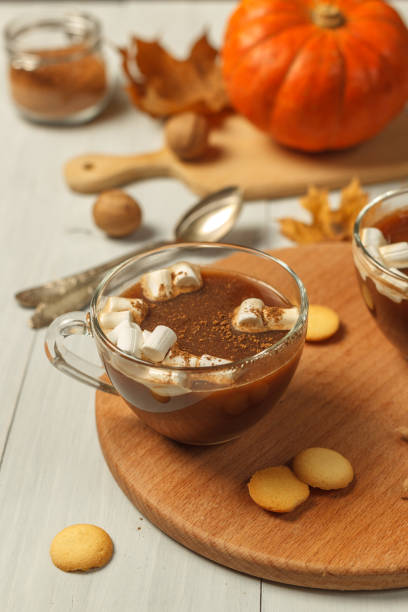 istock Hot cocoa with marshmallows in a glass mug, close-up. On a light wooden table, vertically. Concept of a hot autumn or winter drink 1282380288