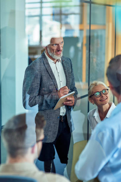 istock Office life. Vertical shot of a handsome mature businessman making some notes while having a meeting with coworkers in the modern office 1282380368