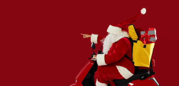 istock Santa claus courier in a protective mask and gloves is quickly carrying a gift boxes  on a red retro motorcycle with a yellow thermo backpack. Safe food delivery. Shows to the left side. Banner 1282381203