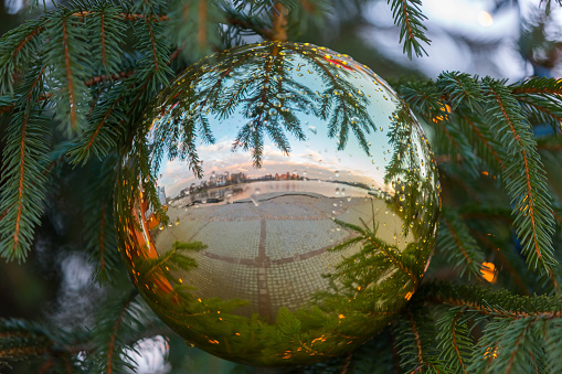 Big Christmas ball with reflections on fir tree branches. Christmas decoration. Lights and garlands on blurred background. Festive New Year's background with free space for text