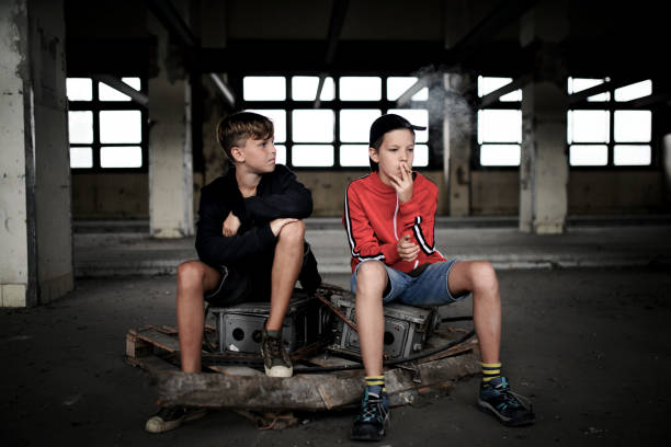 grupo de adolescentes chicos en el interior en edificio abandonado, fumando cigarrillos. - teenage boys adolescence teenager teenagers only fotografías e imágenes de stock