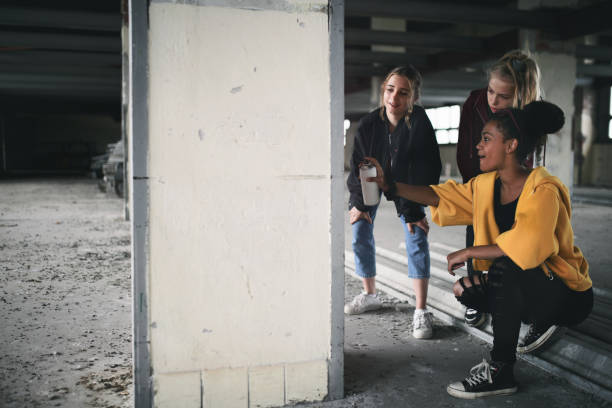 壁にスプレー塗料を使用して、放棄された建物の屋内で10代の女の子のギャングのグループ。 - youth culture gang member adolescence family ストックフォトと画像