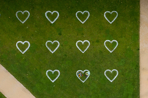 Distanced illustrated hearts for social distancing in public park during coronavirus