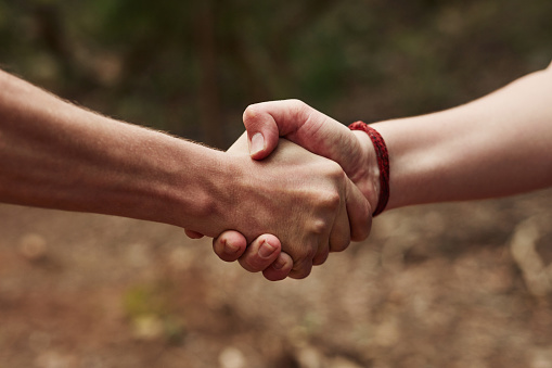 Cropped shot of two unrecognisable men shaking hands out in nature