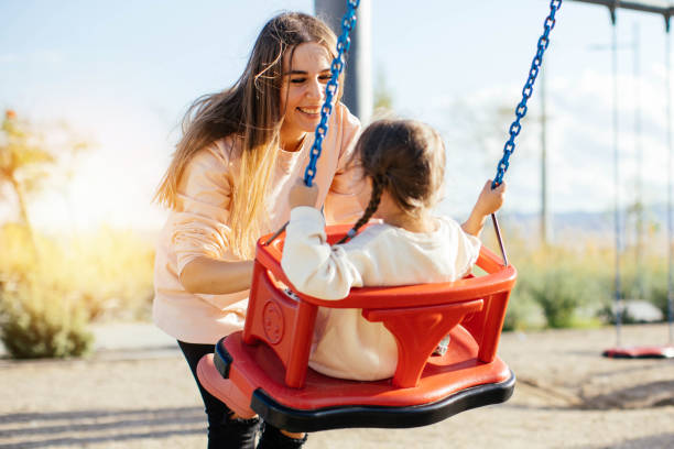 istock Mother pushing daughter on swing in park 1282388584