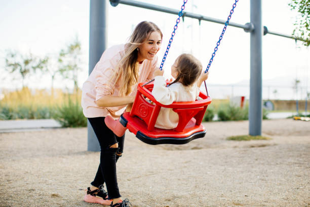 istock Mother pushing daughter on swing in park 1282388651