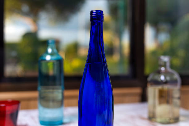 garrafas e vidro de cristal em mesa branca ao lado de uma janela de onde um jardim é visto - liquid crystal display - fotografias e filmes do acervo