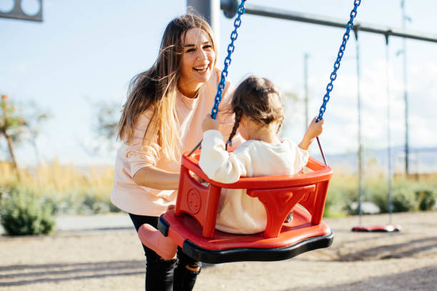 istock Mother pushing daughter on swing in park 1282389360