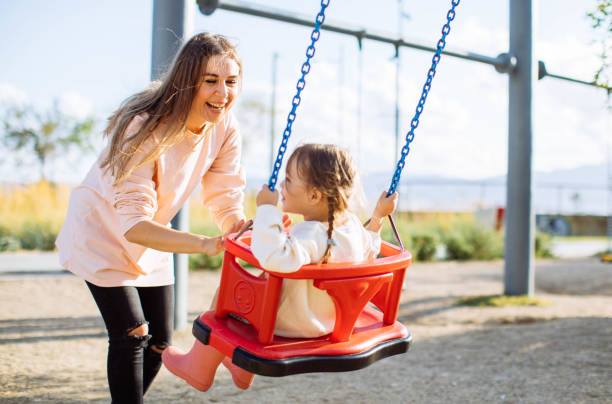 istock Mother pushing daughter on swing in park 1282389414