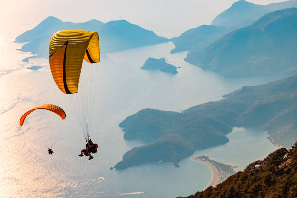 Paraglider tandem flying over the Oludeniz Fethiye, Mugla / Turkey - August 28 2020: Paraglider tandem flying over the Oludeniz at sunset. Aerial view. paraglider stock pictures, royalty-free photos & images