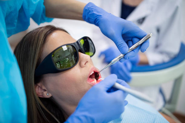 istock Dentist making whitening laser procedure on female patient. 1282395392