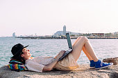 woman working lying down with computer by the sea
