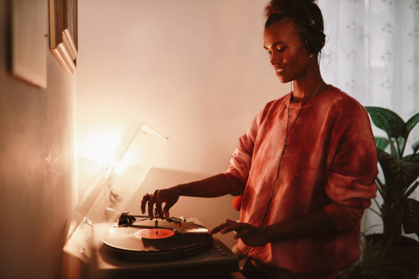 Young woman wearing tie dye shirt playing her record collection at home Young woman playing her vinyl collection at home analog photos stock pictures, royalty-free photos & images