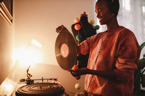 Young woman playing her vinyl collection at home