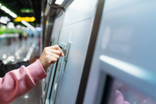 la main de femme insère la pièce de monnaie pour acheter le billet de train de métro dans la machine. t - subway token photos et images de collection