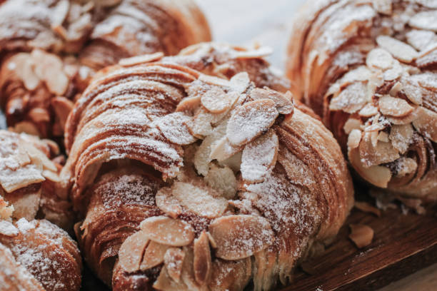 almond croissant bakery fatto in casa sul tavolo. tradizionale vassoio per la colazione francese con oro e croissant croccanti. - pastry crust foto e immagini stock