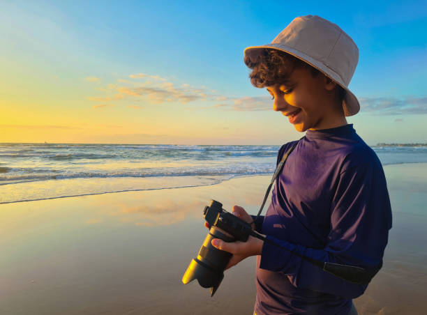 istock Boy photographing on the beach at sunrise 1282411016