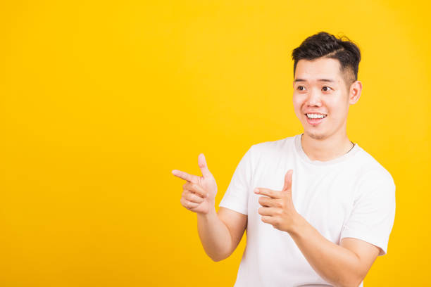 istock young man smiling standing pointing finger to the side away 1282412653