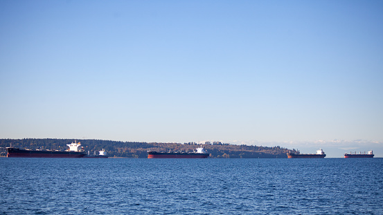 Looking Vancouver's University of British-Columbia (Kitsilano and Spanish Banks) from the North Shore, the shoreline is lined with container freighter ships in British-Columbia, Canada