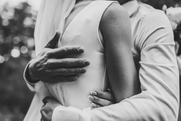 Man hug woman. Goosebumps appeared on body of a young beautiful bride from touch man. Beautiful skin texture. A groom gently embraces girl by shoulders to goosebumps. Close up. Black and white photo.