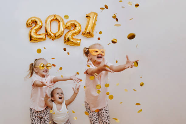 three little girls are enjoying the flying golden confetti. celebrating at home 2021 - child party group of people little girls imagens e fotografias de stock