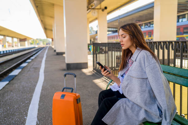 istock Young woman waiting on station and using smart phone 1282421363