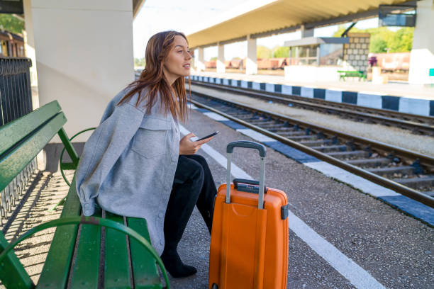 istock Young woman waiting on station and using smart phone 1282421365
