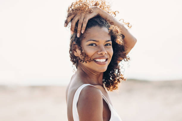 Beautiful young woman walking on the beach on a windy day Beautiful young black woman walking on the beach black women in bathing suits stock pictures, royalty-free photos & images