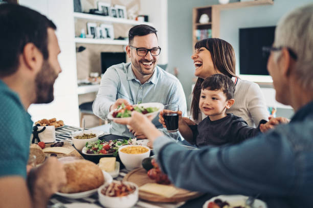 famiglia allargata mangiare insieme - tavolo da soggiorno foto e immagini stock