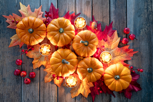 Thanksgiving decoration with pumpkins and candles on illuminated background and a rustic wooden table