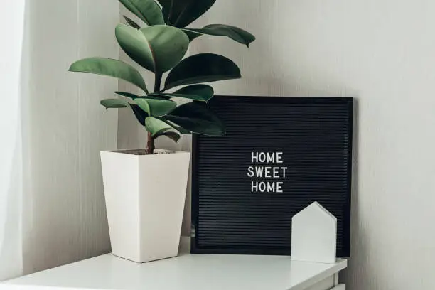 Inspirational quote home sweet home on black letterboard. In light interior, lifestyle. Copy space.