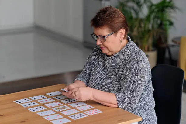 senior woman playing solitaire at home. Happy old lady plays an intellectual game.