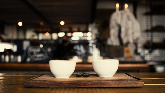 Portrait of two hot coffee cups freshly made and steaming on boards in trendy cafe . High quality photo