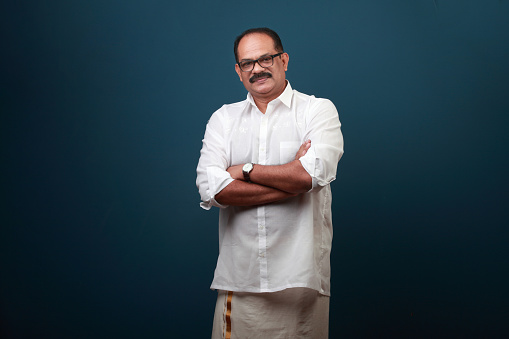 Portrait of a middle aged man wearing Kerala style traditional dress with folded hands