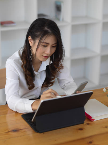 istock Female office worker working with tablet while looking for information in her smartphone 1282436644