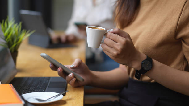 istock Cropped shot of female using smartphone while holding a cup of coffee 1282436709