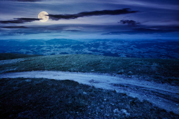 istock mountain road through grassy meadow at night 1282441504