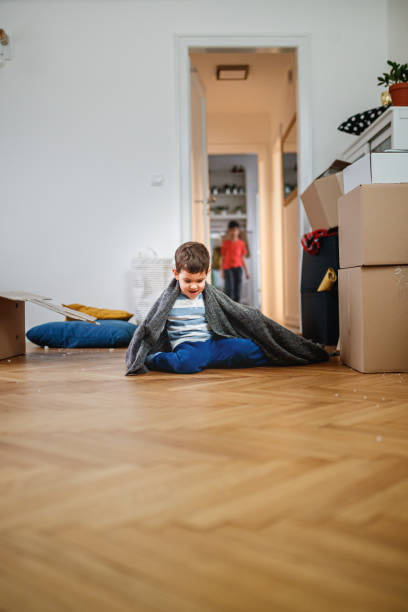 istock Toddler having fun during house move, sitting on floor with blanket over shoulders 1282442568