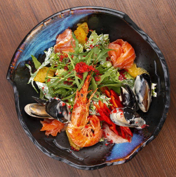 istock Seafood salad: shrimp, mussels and salmon, arugula and oranges. In a decorative plate 1282445114